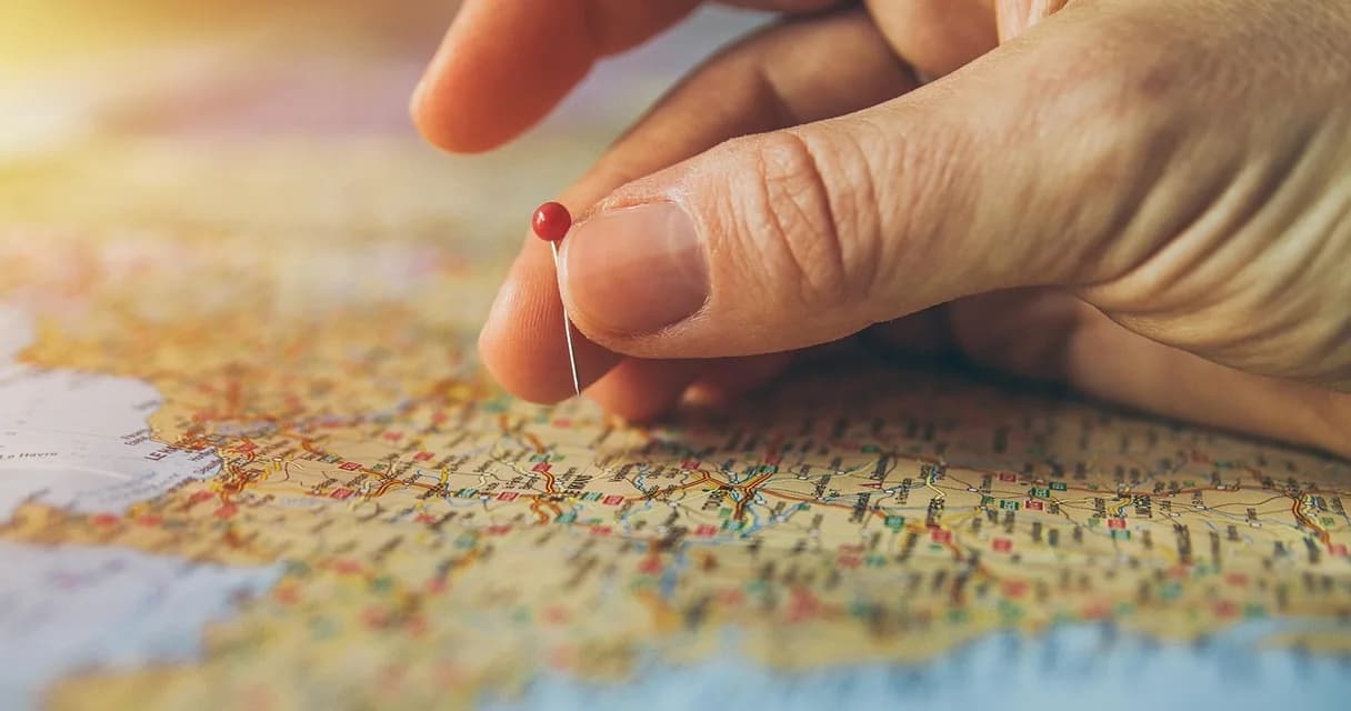 Mão apontando para um mapa com pinos marcando destinos