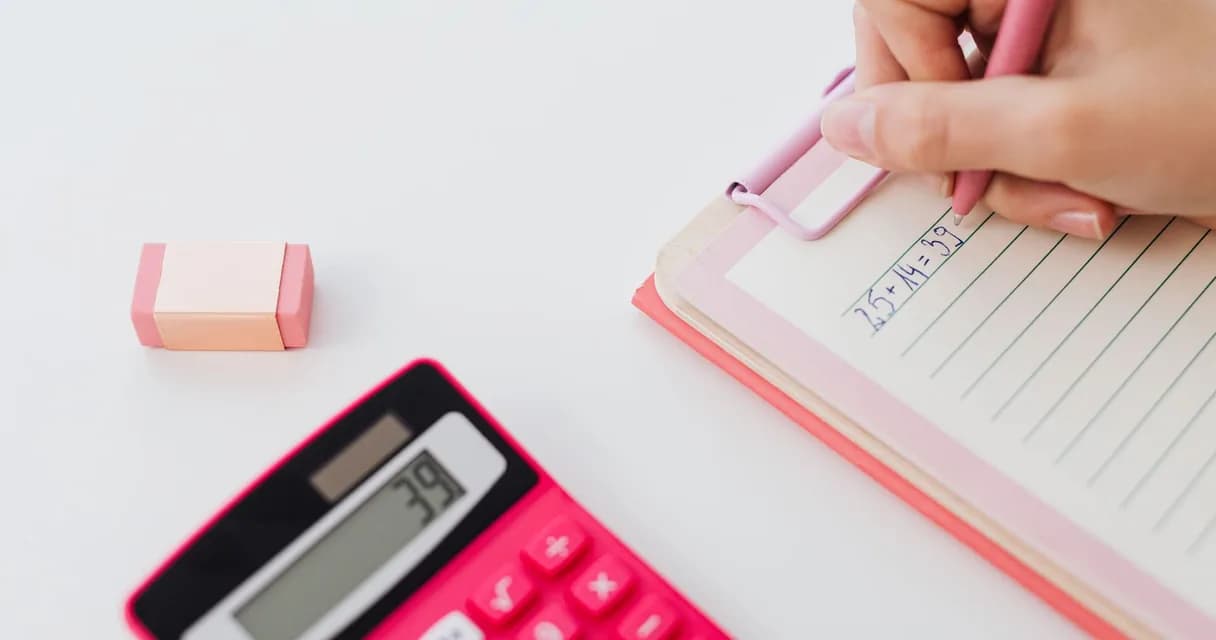 Calculadora rosa e mão escrevendo uma soma em uma prancheta
