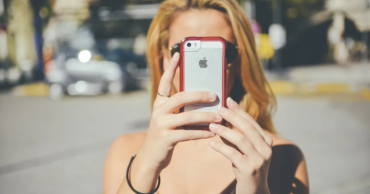 Mulher fotografando com o celular para publicar uma atualização do negócio