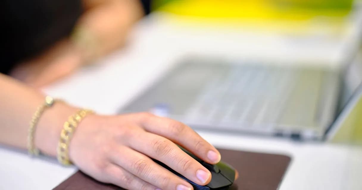 Primeiro link da página: mão sobre o mouse diante de um texto com links na tela do computador