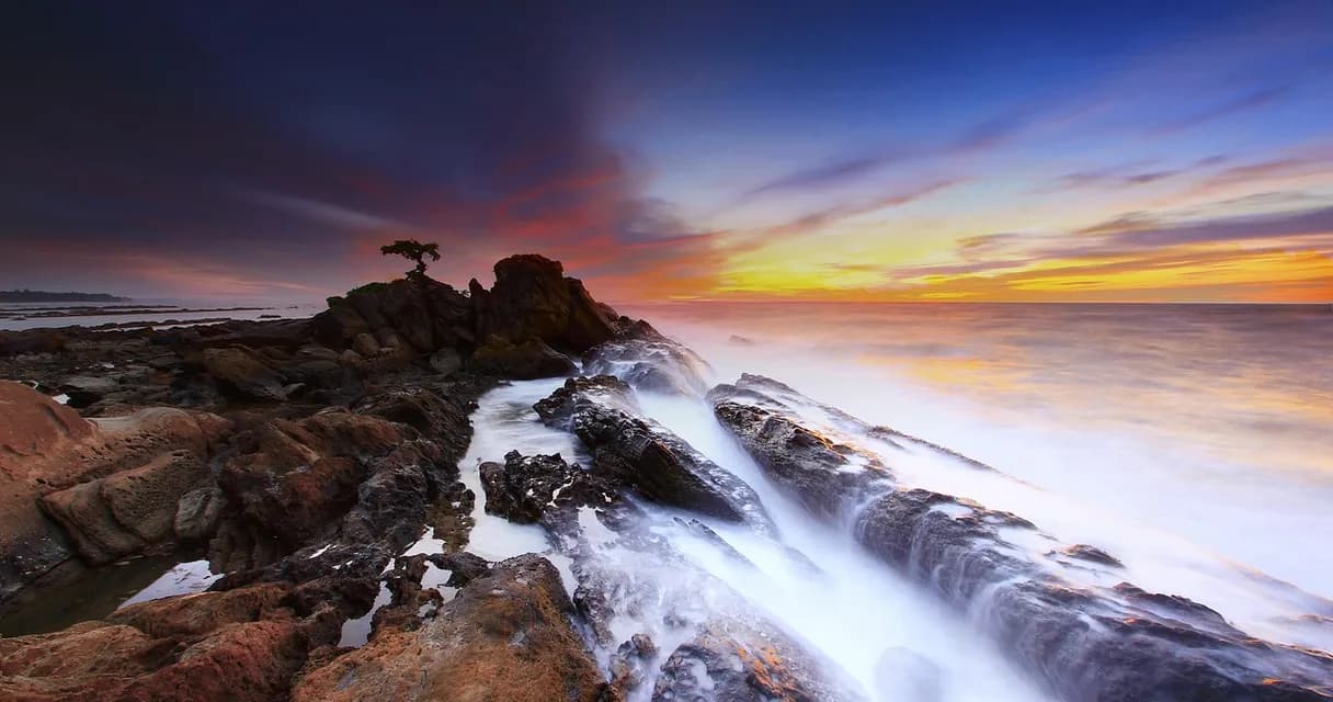 Atualização de spam do Google: ondas do mar batem em rochas ao pôr do sol, como as ondas de impacto de setembro de 2026