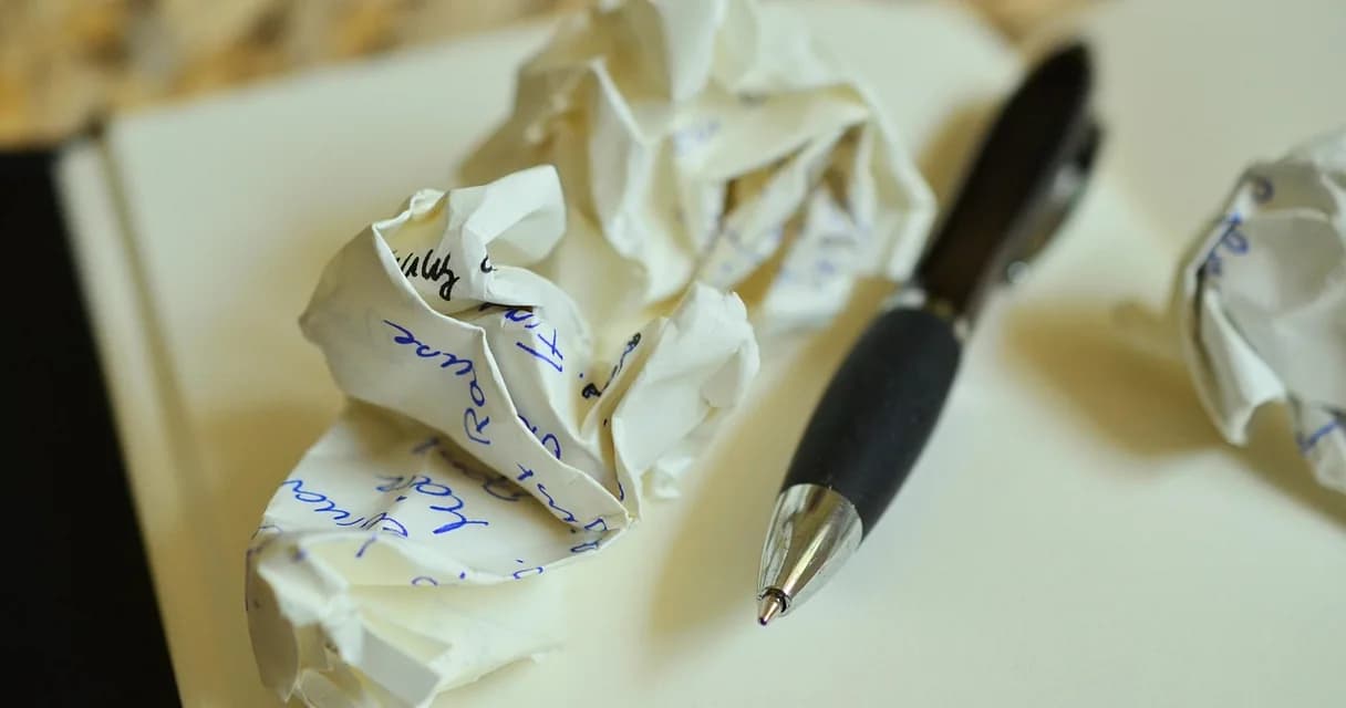 Rascunhos amassados e caneta sobre caderno, revisão para atualizar conteúdo antigo