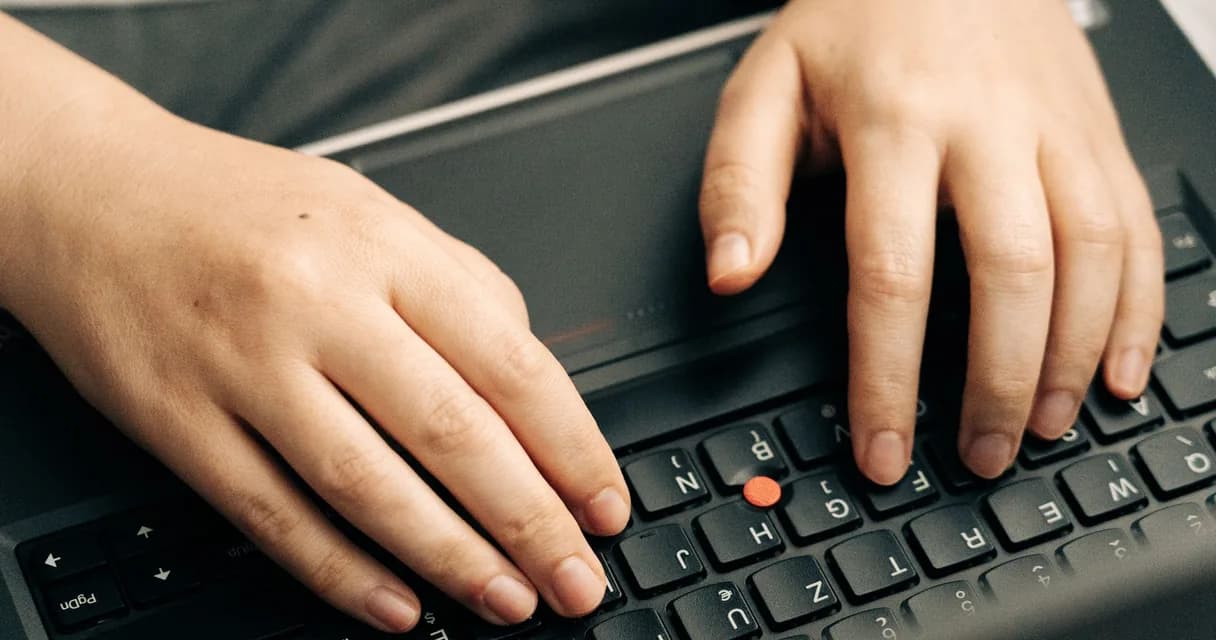 Mãos sobre o teclado de um notebook, prontas para digitar uma busca